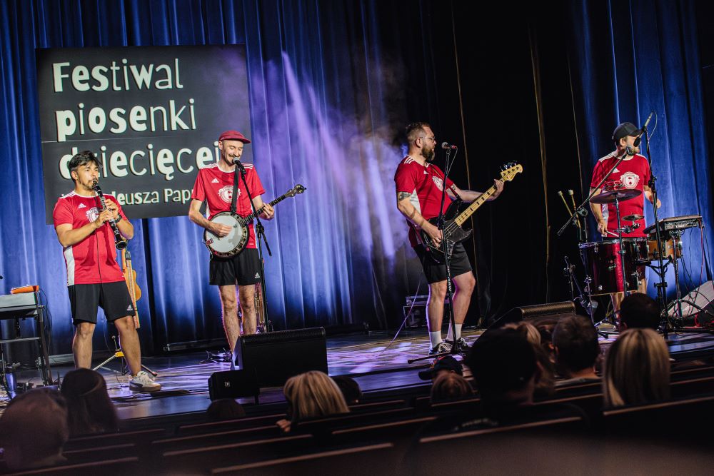 zespół Czereśnie podczas koncertu, 4 mężczyzn w czerwonych strojach sportowych gra na instrumentach
